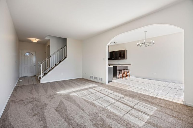 unfurnished living room featuring a chandelier and light carpet