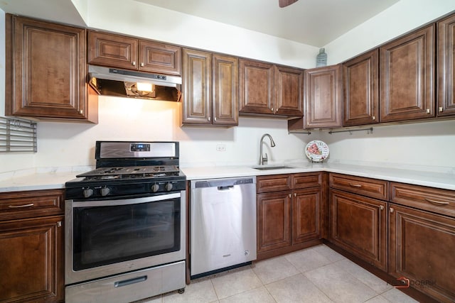 kitchen featuring stainless steel appliances, a sink, light countertops, and under cabinet range hood