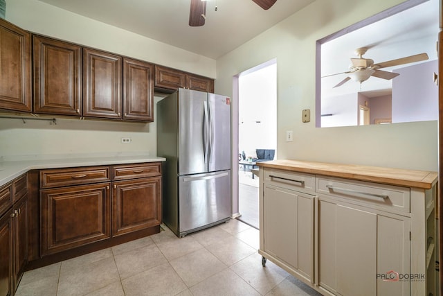 kitchen with freestanding refrigerator, ceiling fan, dark brown cabinetry, and light tile patterned floors