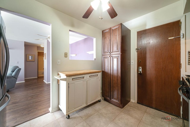 kitchen featuring light tile patterned floors, baseboards, a ceiling fan, and stainless steel gas stove