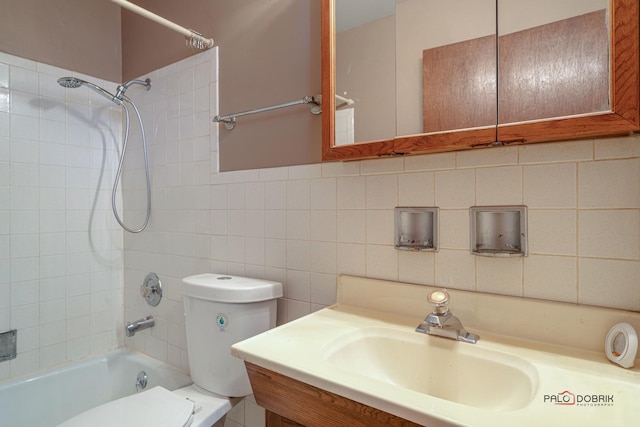 bathroom featuring tub / shower combination, vanity, toilet, and tile walls