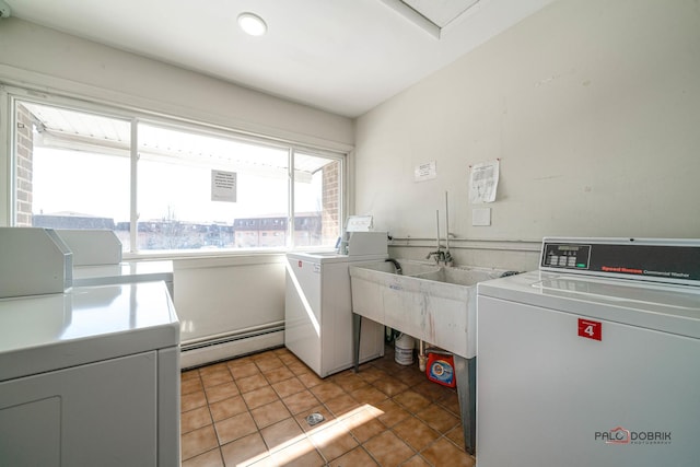 common laundry area with light tile patterned flooring, a baseboard heating unit, and washing machine and clothes dryer