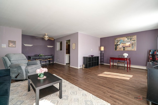 living room with baseboard heating, wood finished floors, a ceiling fan, and baseboards