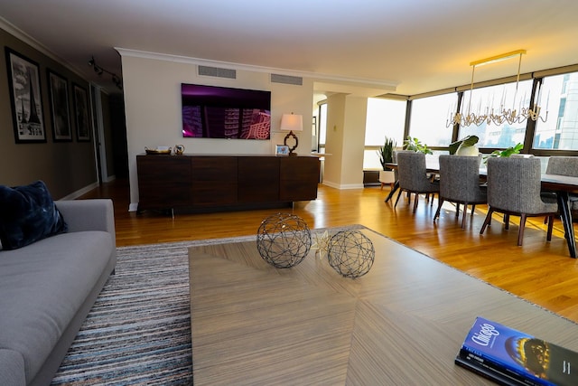 living room featuring light hardwood / wood-style floors, crown molding, and a notable chandelier