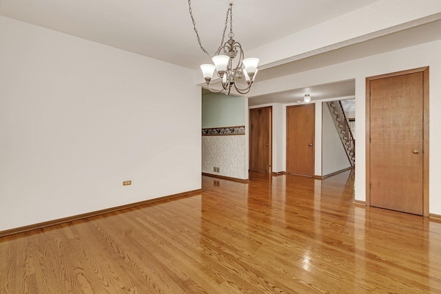 empty room with hardwood / wood-style flooring and an inviting chandelier