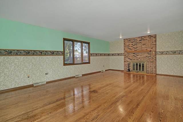 unfurnished living room with a brick fireplace and hardwood / wood-style floors