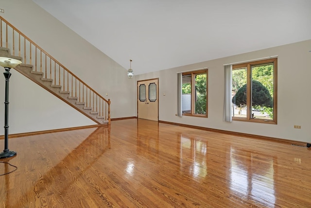 unfurnished living room featuring high vaulted ceiling and hardwood / wood-style floors