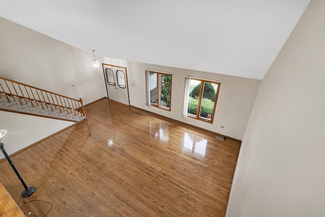 unfurnished living room featuring hardwood / wood-style flooring and vaulted ceiling