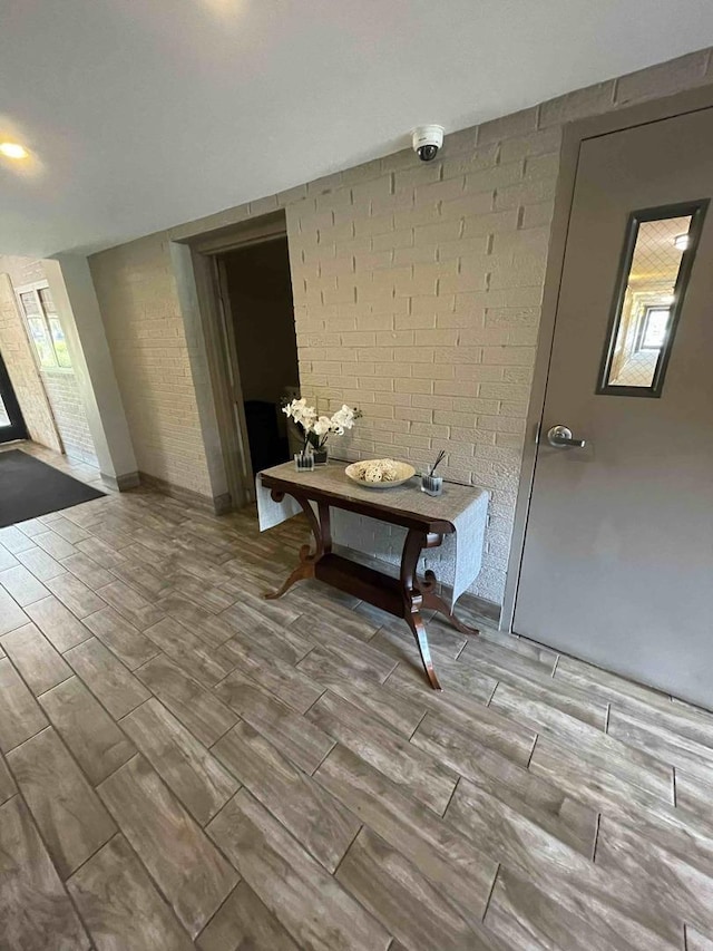 hallway featuring wood tiled floor and brick wall