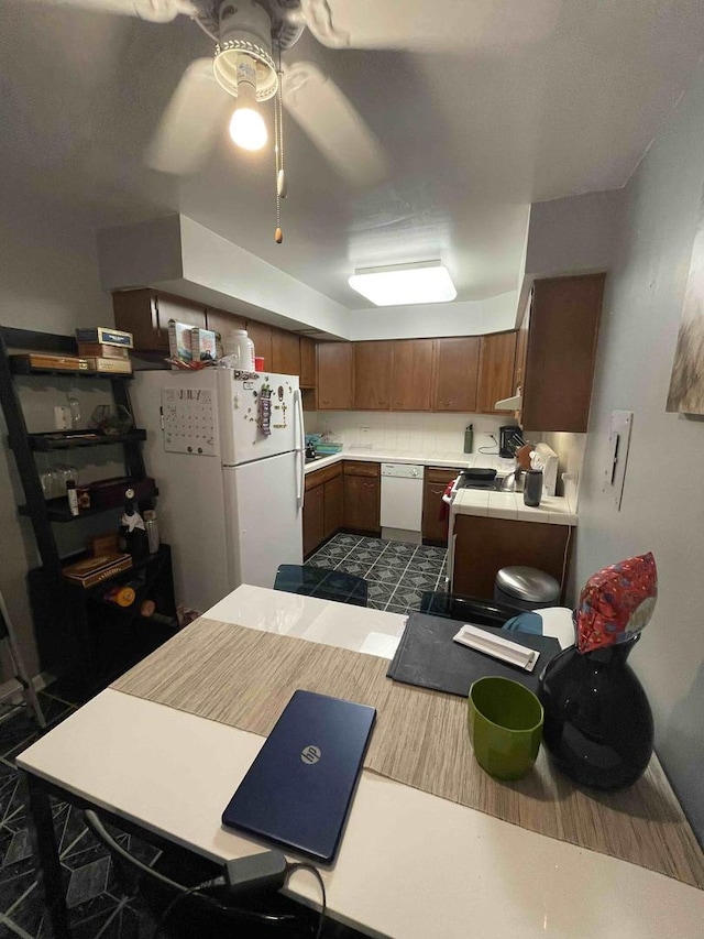 kitchen featuring light countertops, white appliances, a ceiling fan, and brown cabinets