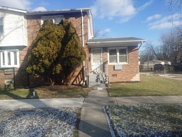 view of front of home featuring crawl space, brick siding, fence, and a front lawn