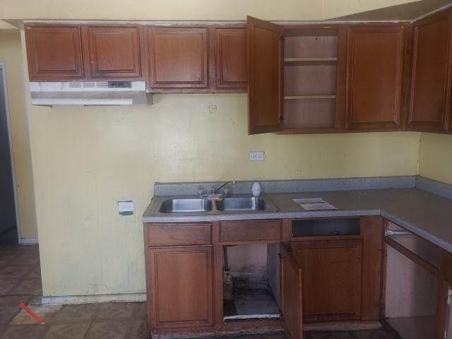 kitchen featuring brown cabinetry, a sink, and under cabinet range hood