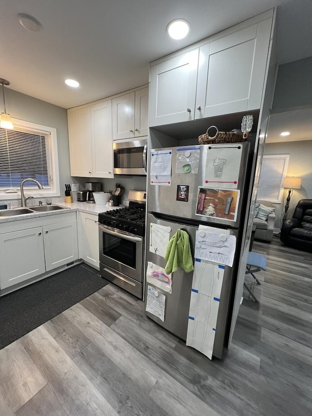 kitchen with white cabinets, wood-type flooring, sink, and stainless steel appliances