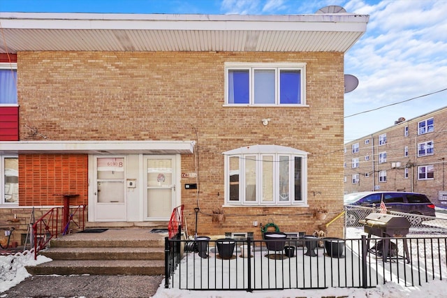 view of front of home featuring fence and brick siding