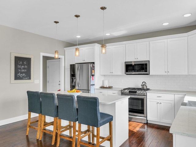 5 Fieldcrest Dr, Monticello, IL 61856 - kitchen featuring appliances with stainless steel finishes, dark wood-style floors, backsplash, a breakfast bar, and white cabinetry