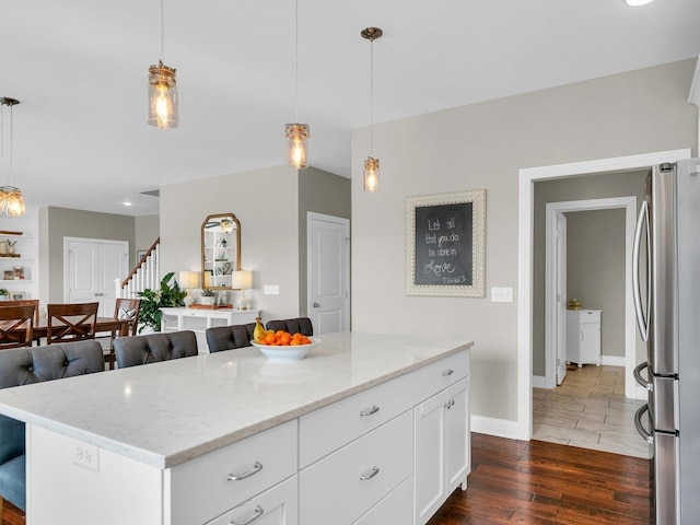 5 Fieldcrest Dr, Monticello, IL 61856 - kitchen featuring freestanding refrigerator, light stone countertops, white cabinets, baseboards, and a kitchen bar