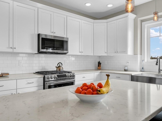 5 Fieldcrest Dr, Monticello, IL 61856 - kitchen featuring appliances with stainless steel finishes, white cabinetry, decorative light fixtures, and light stone countertops