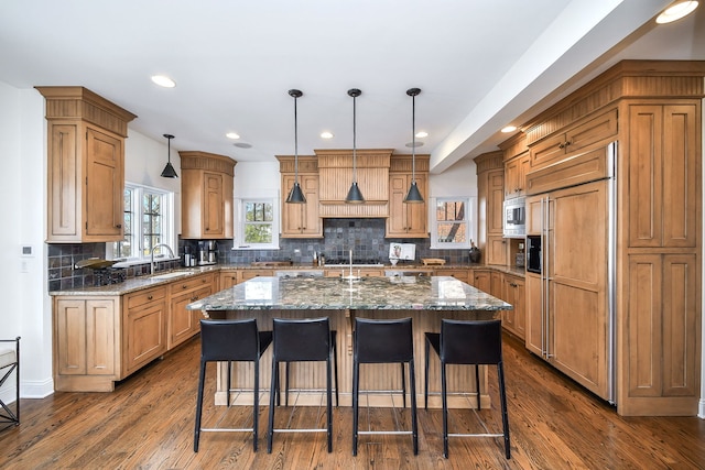 kitchen featuring a kitchen island, a kitchen breakfast bar, dark wood-style flooring, and built in appliances