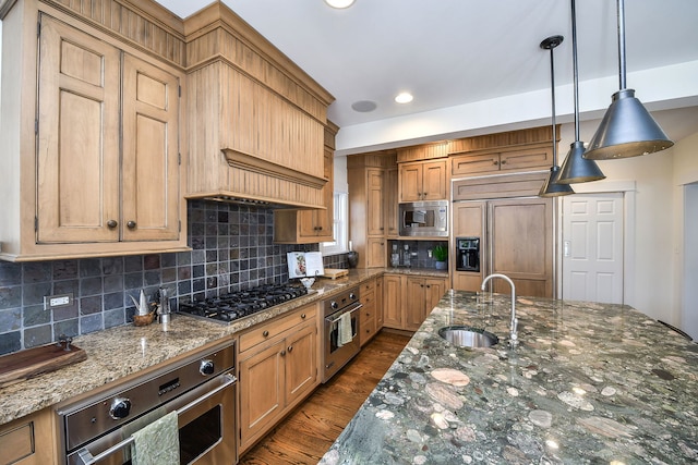 kitchen with built in appliances, dark wood-type flooring, a sink, hanging light fixtures, and tasteful backsplash