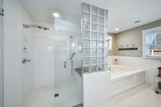 full bath featuring a garden tub, tile patterned flooring, a tile shower, and tile walls