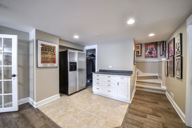 kitchen featuring recessed lighting, white cabinetry, baseboards, dark countertops, and stainless steel fridge