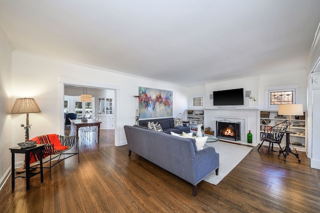 living room with a fireplace with flush hearth, ornamental molding, dark wood finished floors, and baseboards