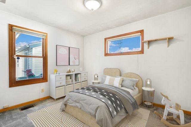 bedroom featuring baseboards, multiple windows, visible vents, and light colored carpet