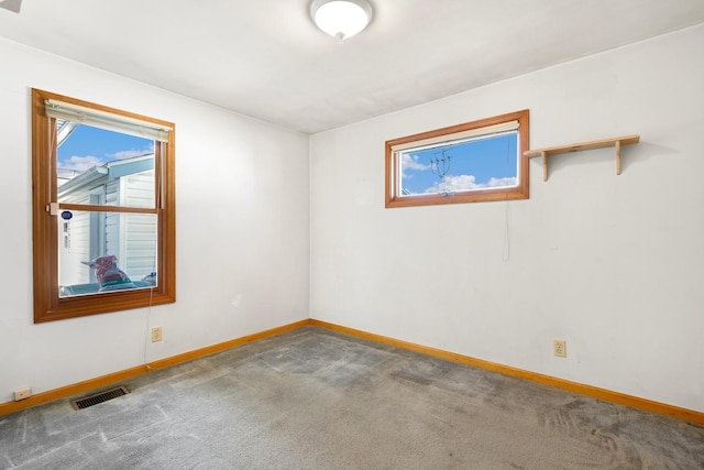 spare room featuring carpet, visible vents, and baseboards