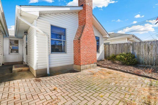 view of side of home with a patio, a chimney, and fence