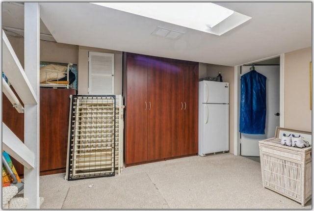 interior space featuring freestanding refrigerator, dark brown cabinets, and a skylight