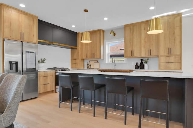 kitchen with light brown cabinets, pendant lighting, a breakfast bar, and stainless steel appliances