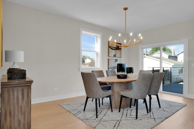 dining area with a healthy amount of sunlight, a chandelier, and light hardwood / wood-style floors