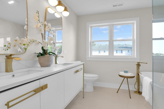 bathroom featuring toilet, a bath, and vanity