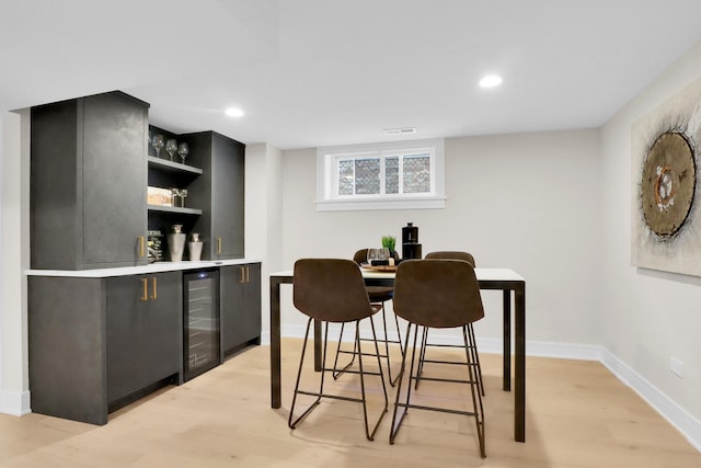 dining space featuring light hardwood / wood-style flooring, beverage cooler, and bar