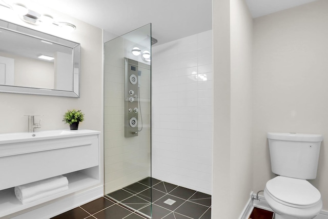 bathroom with toilet, a tile shower, and vanity