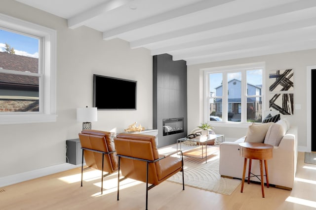 living room featuring beam ceiling, a large fireplace, and light hardwood / wood-style floors