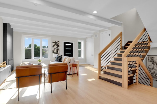 living room with a wealth of natural light, beam ceiling, and light hardwood / wood-style flooring