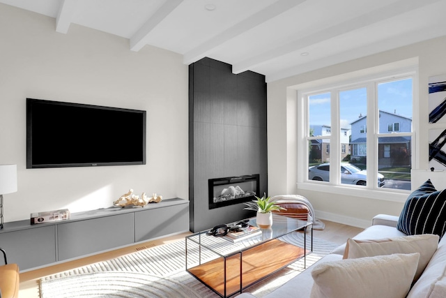 living room featuring beam ceiling and light hardwood / wood-style flooring