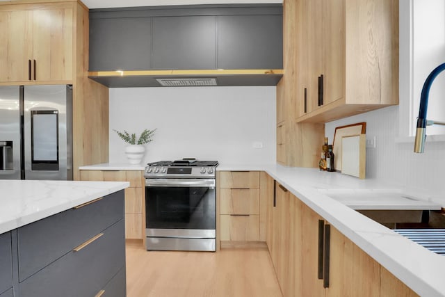 kitchen with light stone counters, stainless steel appliances, and light brown cabinets