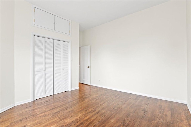 unfurnished bedroom with baseboards, a closet, and wood finished floors