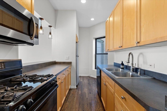 kitchen with a sink, dark countertops, black appliances, and dark wood-style floors