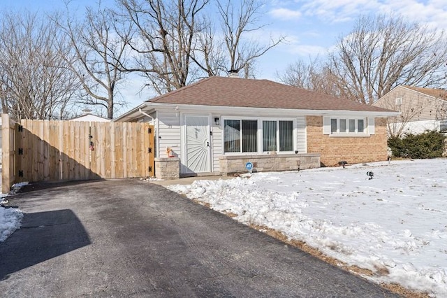 view of front of home with brick siding, a shingled roof, driveway, and stone siding