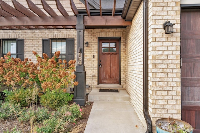 property entrance featuring brick siding, a garage, and a pergola