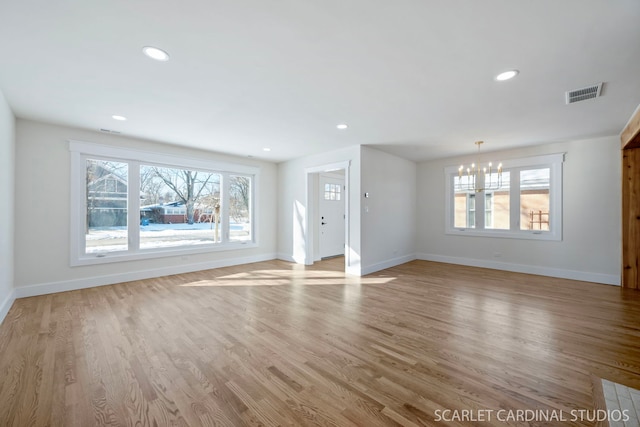 unfurnished living room with light wood-style floors, a healthy amount of sunlight, visible vents, and baseboards