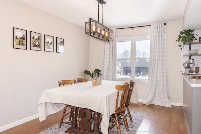 dining space with baseboards and wood finished floors