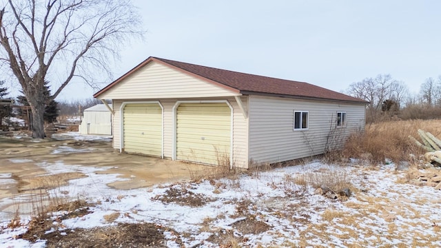 snow covered garage featuring a detached garage