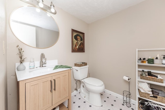 bathroom with vanity, toilet, baseboards, and a textured ceiling