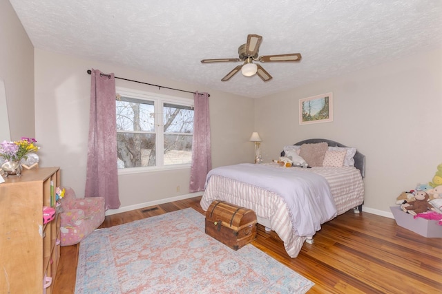 bedroom with baseboards, wood finished floors, and a textured ceiling