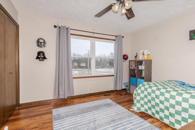 bedroom with ceiling fan, a closet, dark wood-style floors, and a textured ceiling