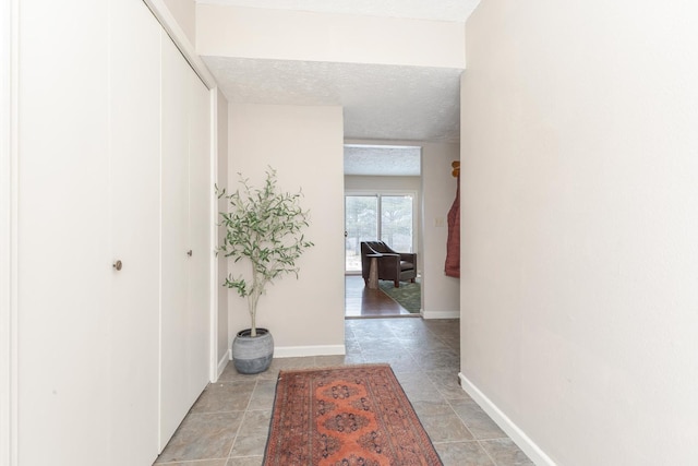 corridor featuring baseboards and a textured ceiling